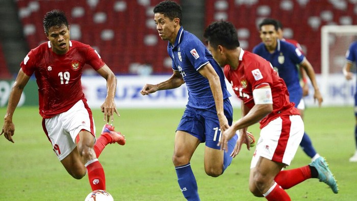 Bordin Phala of Thailand, center, controls the ball past Fachruddin Aryanto of Indonesia during the AFF Suzuki Cup 2020 final first leg soccer match between Indonesia and Thailand in Singapore, Wednesday, Dec. 29, 2021. (AP Photo/Suhaimi Abdullah)