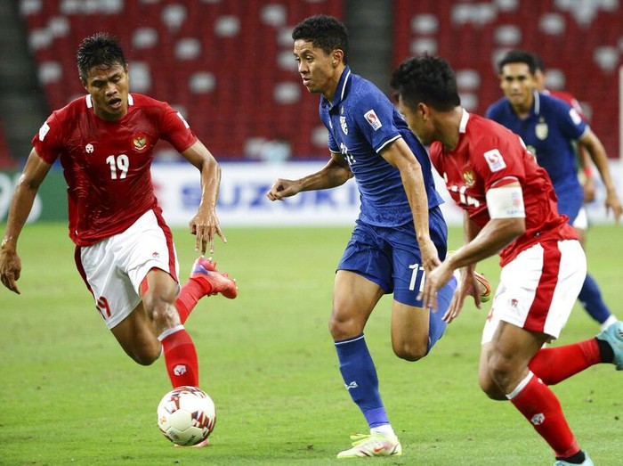 Bordin Phala of Thailand, center, controls the ball past Fachruddin Aryanto of Indonesia during the AFF Suzuki Cup 2020 final first leg soccer match between Indonesia and Thailand in Singapore, Wednesday, Dec. 29, 2021. (AP Photo/Suhaimi Abdullah)