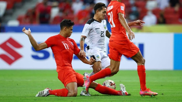 SINGAPORE, SINGAPORE - DECEMBER 14: Paulo Domingos Gali #21 of Timor-Leste shoots the ball against Irfan Fandi #17 and Safuwan Baharudin #21 of Singapore during the second half of their AFF Suzuki Cup Group A game at the National Stadium on December 14, 2021 in Singapore. (Photo by Yong Teck Lim/Getty Images)