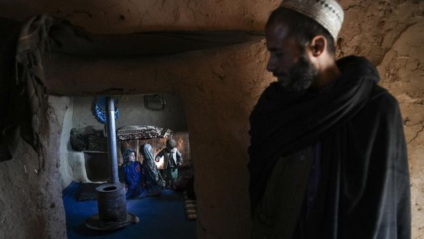 Hamid Abdullah berdiri di luar ruangan tempat anak-anaknya bermain di sebuah pemukiman dekat Herat, Afghanistan (16/12/2021). Abdullah menjual putrinya yang masih kecil untuk dijodohkan karena sangat membutuhkan uang untuk mengobati istrinya yang sakit kronis dan hamil anak kelima mereka . (AP/Mstyslav Chernov)