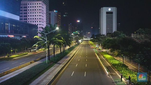 Seorang pedang kopi keliling melewati ruas jalan utama di area jalan Sudirman-Thamrin, Jakarta, Sabtu (1/1/2022). Sejak pukul 22.00 WIB terpantau kendaraan dan penduduk  sangat lengang. Kendaraan operasional polisi tampak menyusuri ruas-ruas jalan nan menjadi titik penutupan jalan.Malam pergantian tahun 2021 menuju 2022 di pusat Kota Jakarta berjalan sepi. Pemerintah Provinsi DKI Jakarta berbareng Polda Metro Jaya menutup 11 ruas jalan sejak pukul 22.00 WIB.Dari pantauan dilokasi sejumlah ruas jalan di Jakarta terpantau lengang. Tak banyak kendaraan melintas.   Kendaraan operasional polisi tampak menyusuri ruas-ruas jalan nan menjadi titik penutupan jalan (CNBC Indonesia/ Tri Susilo)