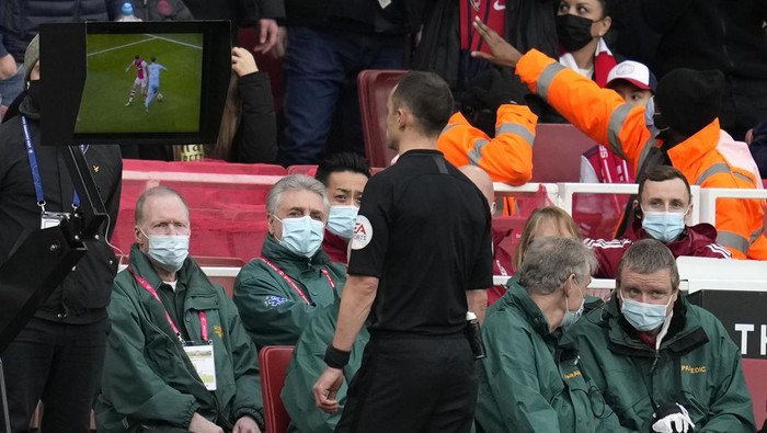 Referee Stuart Atwell consults VAR during the Premier League soccer match between Arsenal and Manchester City at the Emirates Stadium, in London, England, Saturday Jan. 1, 2022. (AP Photo/Matt Dunham)