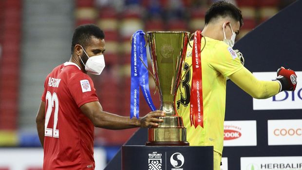 Yabes Roni Malaifani of Indonesia, left, touches the trophy during the prize presentation after the AFF Suzuki Cup 2020 final second leg match between Thailand and Indonesia in Singapore, Saturday, Jan. 1, 2022. (AP Photo/Suhaimi Abdullah)