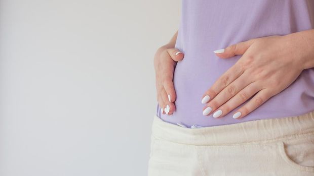 Pregnant woman in the early stages touches the belly with her hands. First and second trimester of pregnancy.