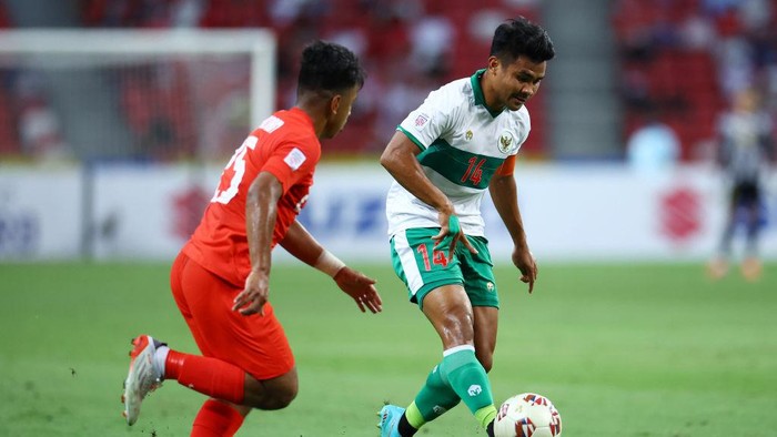 SINGAPORE, SINGAPORE - DECEMBER 22: Asnawi Mangkualam Bahar #14 of Indonesia controls the ball against Nur Adam Abdullah #25 of Singapore in the first half during the first leg of their AFF Suzuki Cup semifinal at the National Stadium on December 22, 2021 in Singapore. (Photo by Yong Teck Lim/Getty Images)