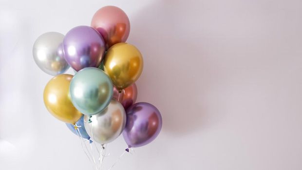 helium balloons in metallic colors on a mauve background, copy space on the right
