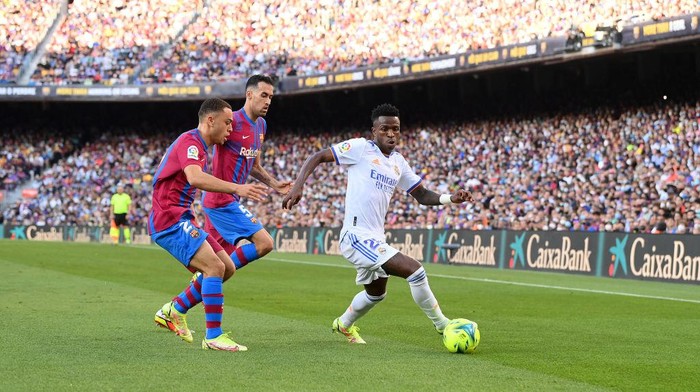 BARCELONA, SPAIN - OCTOBER 24: Vinicius Junior of Real Madrid holds off Sergino Dest and Sergio Busquets of FC Barcelona during the LaLiga Santander match between FC Barcelona and Real Madrid CF at Camp Nou on October 24, 2021 in Barcelona, Spain. (Photo by David Ramos/Getty Images)