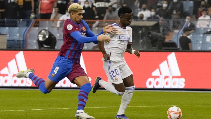Real Madrids Vinicius Junior in action to score by Barcelonas Ronald Araujo during the Spanish Super Cup semi final soccer match between Barcelona and Real Madrid at King Fahd stadium in Riyadh, Saudi Arabia, Wednesday, Jan. 12, 2022. (AP Photo/Hassan Ammar)