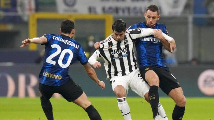 Juventus Alvaro Morata, center, challenges for the ball with Inter Milans Stefan de Vrij, right, and Inter Milans Hakan Calhanoglu during the Italian Super Cup final soccer match between Inter Milan and Juventus at the San Siro Stadium, in Milan, Italy, Wednesday, Jan. 12, 2022. (AP Photo/Luca Bruno)