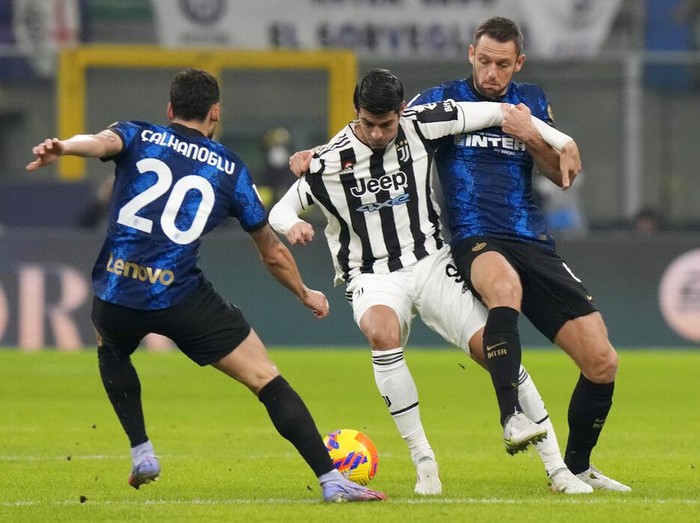 Juventus Alvaro Morata, center, challenges for the ball with Inter Milans Stefan de Vrij, right, and Inter Milans Hakan Calhanoglu during the Italian Super Cup final soccer match between Inter Milan and Juventus at the San Siro Stadium, in Milan, Italy, Wednesday, Jan. 12, 2022. (AP Photo/Luca Bruno)