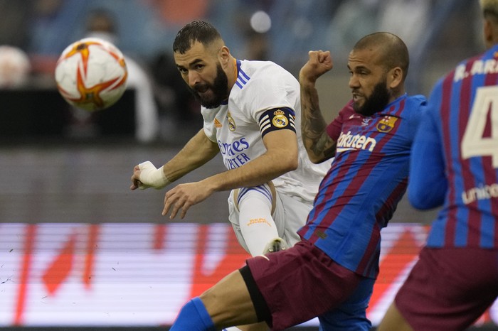 Real Madrid's Karim Benzema shoots by Barcelona's Dani Alves during the Spanish Super Cup semi final soccer match between Barcelona and Real Madrid at King Fahd stadium in Riyadh, Saudi Arabia, Wednesday, Jan. 12, 2022. (AP Photo/Hassan Ammar)