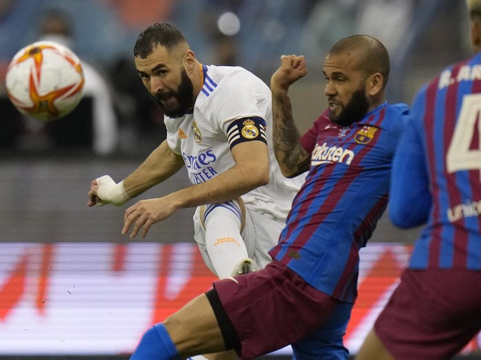 Real Madrid's Karim Benzema shoots by Barcelona's Dani Alves during the Spanish Super Cup semi final soccer match between Barcelona and Real Madrid at King Fahd stadium in Riyadh, Saudi Arabia, Wednesday, Jan. 12, 2022. (AP Photo/Hassan Ammar)