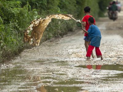 Aksi Anak-anak Kuras Air dari Jalan Berlubang di Kabupaten Bekasi