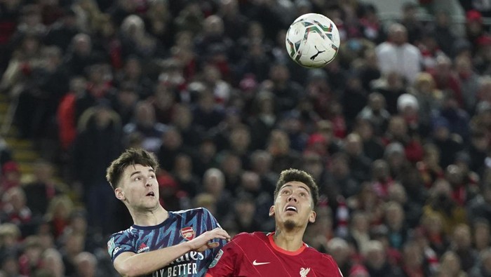 Liverpools Roberto Firmino, right, jumps for a header with Arsenals Kieran Tierney during the EFL Cup semifinal, first leg soccer match between Liverpool and Arsenal at the Anfield Stadium in Liverpool, Thursday, Jan.13, 2022.(AP Photo/Jon Super)