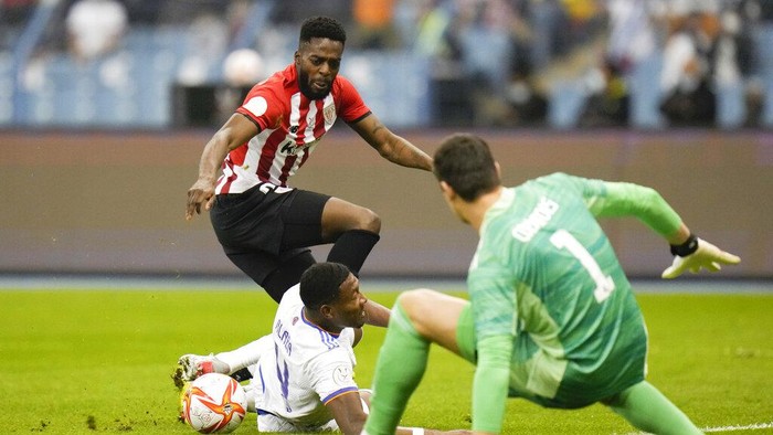 Athletic Bilbao's Inaki Williams shoots in front of Real Madrid's goalkeeper Thibaut Courtois during the Spanish Super Cup final soccer match between Real Madrid and Athletic Bilbao at King Fahd stadium in Riyadh, Saudi Arabia, Sunday, Jan. 16, 2022. (AP Photo/Hassan Ammar)