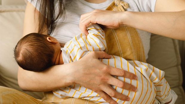 Newborn baby boy sucking milk from mothers breast. Portrait of mom and breastfeeding baby. Concept of healthy and natural baby breastfeeding nutrition.