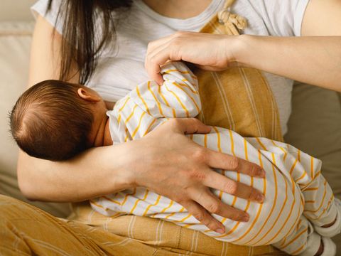 Newborn baby boy sucking milk from mothers breast. Portrait of mom and breastfeeding baby. Concept of healthy and natural baby breastfeeding nutrition.