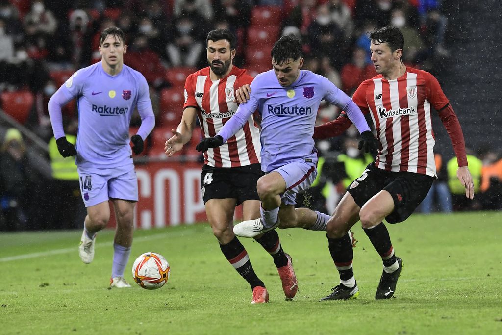 Barcelona's Pedri, center, is challenged by Athletic Bilbao's Mikel Vesga, right and Athletic Bilbao's Inigo Martinez during the Spanish Copa del Rey Cup round of 16 soccer match between Athletic Club and Barcelona at the San Mames stadium in Bilbao, Friday, Jan. 21, 2022. (AP Photo/Alvaro Barrientos)