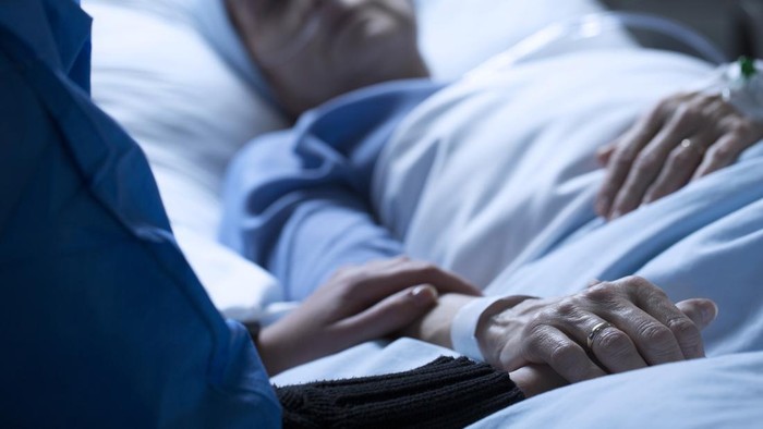 Ilustrasi Pasien Sakit Meninggal Young woman holding hands and saying goodbye to her dying of cancer mother in hospice