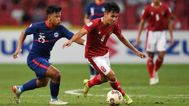 Singapore's Nur Adam Abdullah (L) fights for the ball with Indonesia's Witan Sulaeman during the second leg of the AFF Suzuki Cup 2020 football semi-final match between Singapore and Indonesia at the National Stadium in Singapore on December 25, 2021. (Photo by Roslan RAHMAN / AFP)