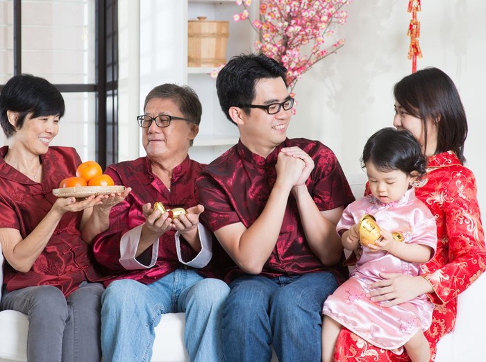 Celebrating Chinese new year. Happy Asian multi generations family in red cheongsam reunion and greeting at home.
