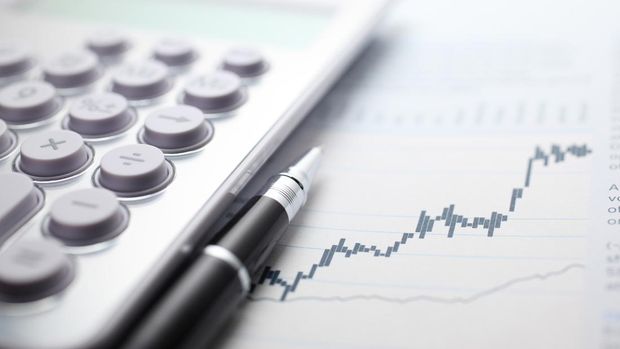 ilustrasi inflasi Calculator and ballpoint pen on stock market data chart.