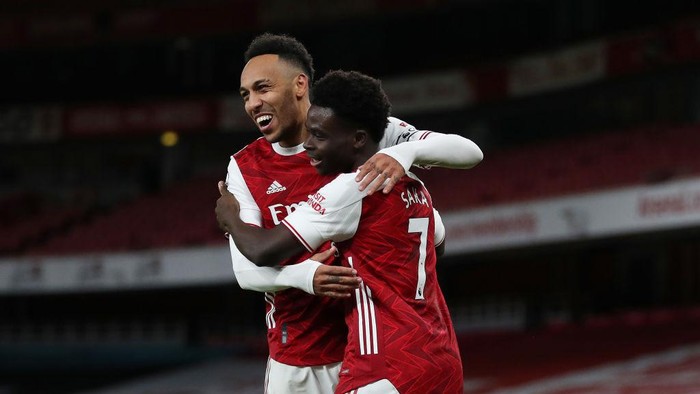 LONDON, ENGLAND - JANUARY 18: Bukayo Saka of Arsenal (R) celebrates with teammate Pierre-Emerick Aubameyang after scoring their teams second goal during the Premier League match between Arsenal and Newcastle United at Emirates Stadium on January 18, 2021 in London, England. Sporting stadiums around England remain under strict restrictions due to the Coronavirus Pandemic as Government social distancing laws prohibit fans inside venues resulting in games being played behind closed doors. (Photo by Catherine Ivill/Getty Images)