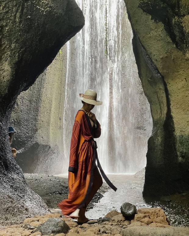 Stylish dengan Long Kimono dan Topi sambil Berpose depan Air Terjun