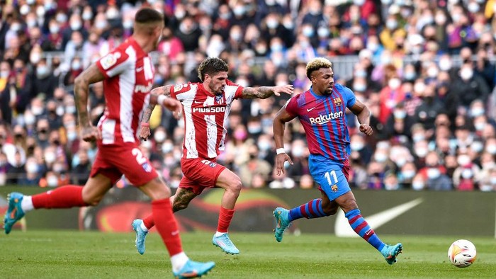 Barcelonas Spanish forward Adama Traore (R) runs with the ball ahead Atletico Madrids Spanish defender Sergio Diez Roldan (C) during the Spanish league football match between FC Barcelona and Club Atletico de Madrid at the Camp Nou stadium in Barcelona on February 6, 2022. (Photo by Josep LAGO / AFP)