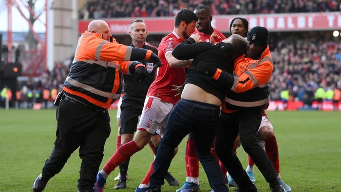 NOTTINGHAM, ENGLAND - FEBRUARY 06: A fan is apprehended on the pitch after attacking a Nottingham Forest player during the Emirates FA Cup Fourth Round match between Nottingham Forest and Leicester City at City Ground on February 06, 2022 in Nottingham, England. (Photo by Laurence Griffiths/Getty Images)
