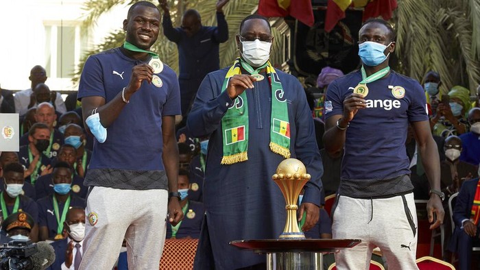 Senegals President Macky Sall, center, stands with footballers Kalidou Koulibaly, left, and Sadio Mane, right, at a ceremony to mark the countrys African Cup win, at the presidential palace in Dakar, Senegal Tuesday, Feb. 8, 2022. Senegal won its first African Cup Sunday by beating Egypt 4-2 in a penalty shootout with Sadio Mane scoring the decisive penalty. (AP Photo/Stefan Kleinowitz)