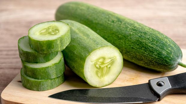 Cucumber vegetable food cut in slice and knife on cutting board for cooking in kitchen.