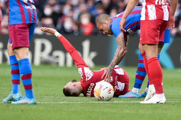 Atletico Madrids Belgian midfielder Yannick Ferreira-Carrasco lies on the ground after a fault by Barcelonas Brazilian defender Dani Alves (R) during the Spanish league football match between FC Barcelona and Club Atletico de Madrid at the Camp Nou stadium in Barcelona on February 6, 2022. (Photo by Josep LAGO / AFP)