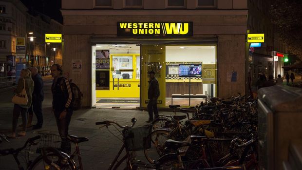 Western Union Munich, Germany - October 26, 2013: People and bicycles outside a Western Union office in Munich, Germany. Western Union works with local agents to facilitate transferring money internationally. It operates in 200 countries worldwide.