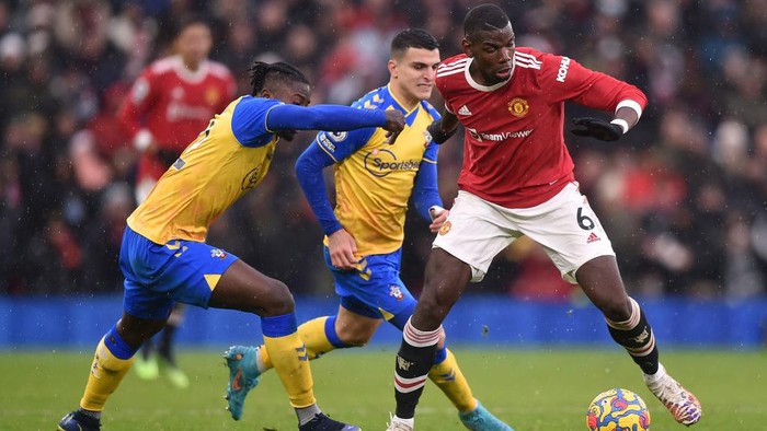 MANCHESTER, ENGLAND - FEBRUARY 12: Paul Pogba of Manchester United runs with the ball from Mohammed Salisu and Mohamed Elyounoussi of Southampton during the Premier League match between Manchester United and Southampton at Old Trafford on February 12, 2022 in Manchester, England. (Photo by Nathan Stirk/Getty Images)