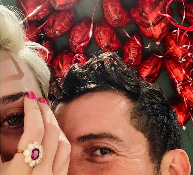 berlatar balon merah berbentuk hati, Katy Perry memamerkan cincin pertunangannya dengan Orlando Bloom
