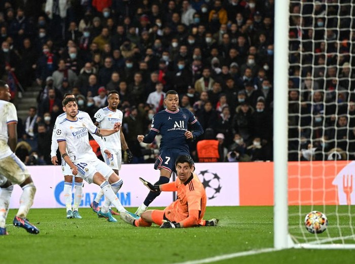 PARIS, FRANCE - FEBRUARY 15: Kylian Mbappe of Paris Saint-Germain scores their team's first goal past Thibaut Courtois of Real Madrid during the UEFA Champions League Round Of Sixteen Leg One match between Paris Saint-Germain and Real Madrid at Parc des Princes on February 15, 2022 in Paris, France. (Photo by Shaun Botterill/Getty Images)