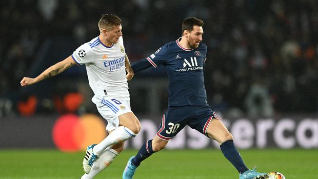 PARIS, FRANCE - FEBRUARY 15: Lionel Messi of Paris Saint-Germain runs with the ball from Toni Kroos of Real Madrid during the UEFA Champions League Round Of Sixteen Leg One match between Paris Saint-Germain and Real Madrid at Parc des Princes on February 15, 2022 in Paris, France. (Photo by Shaun Botterill/Getty Images)