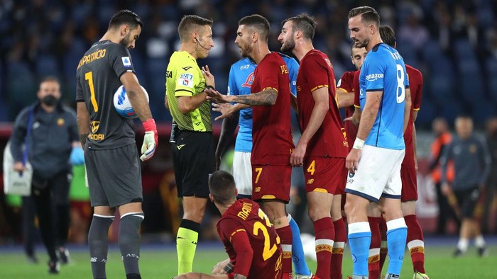 ROME, ITALY - OCTOBER 24: Match Referee, Davide Massa interacts with Lorenzo Pellegrini of AS Roma as Gianluca Mancini of AS Roma sits on the floor during the Serie A match between AS Roma and SSC Napoli at Stadio Olimpico on October 24, 2021 in Rome, Italy. (Photo by Paolo Bruno/Getty Images)