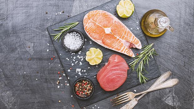 Raw tuna and salmon steak and ingredients for cooking on a dark background. Top view