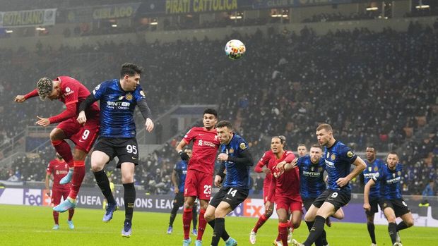 Liverpool's Roberto Firmino, left, scores his side's opening goal during the Champions League, round of 16, first leg soccer match between Inter Milan and Liverpool at the San Siro stadium in Milan, Italy, Wednesday, Feb. 16, 2022. (AP Photo/Antonio Calanni)