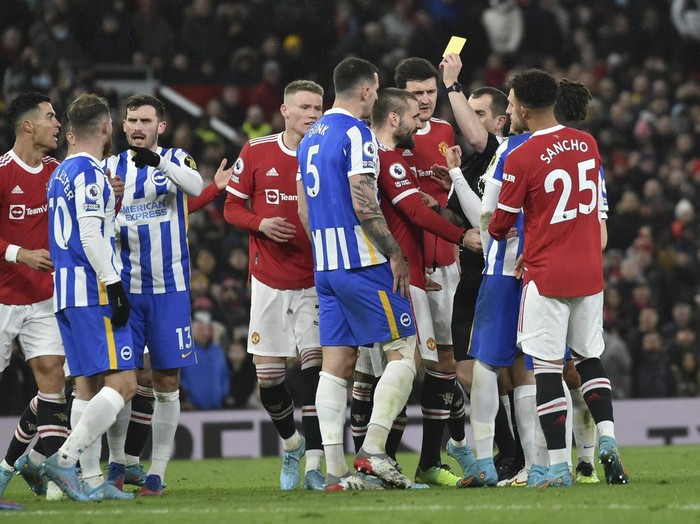 Referee Peter Bankes shows a yellow card to Brightons Lewis Dunk, center 5, before upgrading it to a red card after watching a replay during the English Premier League soccer match between Manchester United and Brighton & Hove Albion at Old Trafford stadium, in Manchester, England, Tuesday, Feb. 15, 2022. (AP Photo/Rui Vieira)