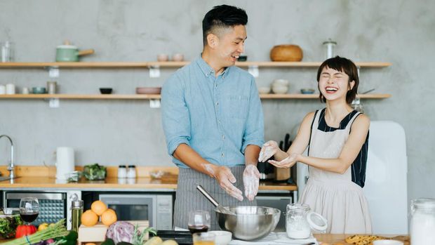 Affectionate young Asian couple having fun while baking together in a domestic kitchen