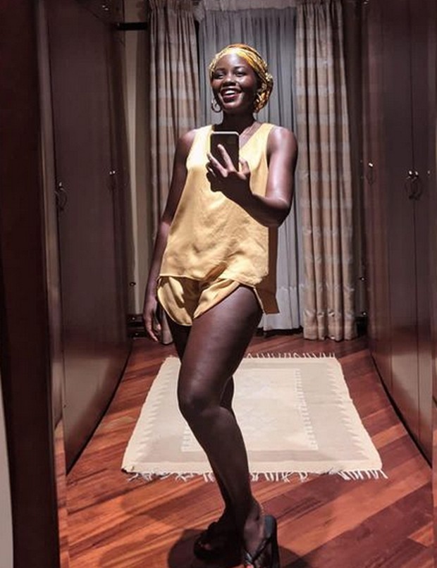 Saat diwawancara secara virtual, Lupita Nyongo memadukan setelan rumah dan turban berwarna kuning serta anting bulat besar sebagai asesorisnya