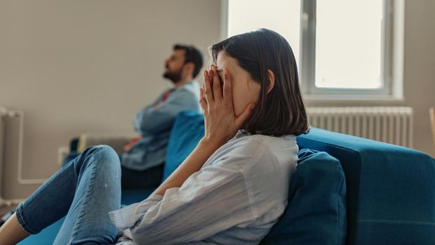 Unhappy Couple After an Argument in the Living Room at Home. Sad Pensive Young Girl Thinking of Relationships Problems Sitting on Sofa With Offended Boyfriend, Conflicts in Marriage, Upset Couple After Fight Dispute, Making Decision of Breaking Up Get Divorced