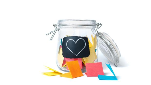 Open Bank with colorful stickers on a white background with white chalk-drawn heart