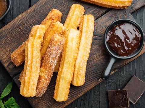 Churros with chocolate, Traditional Spanish cusine, on black wooden table background, top view flat lay
