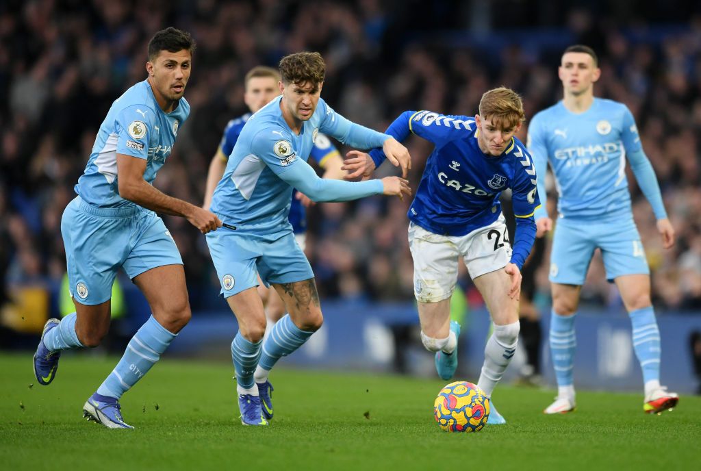 LIVERPOOL, ENGLAND - FEBRUARY 26: Anthony Gordon of Everton is challenged by John Stones and Rodrigo of Manchester City during the Premier League match between Everton and Manchester City at Goodison Park on February 26, 2022 in Liverpool, England. (Photo by Michael Regan/Getty Images)