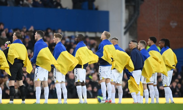 Liga Inggris untuk Ukraina LIVERPOOL, ENGLAND - FEBRUARY 26: Everton players line up on the pitch with Ukrainian flags to indicate peace and sympathy with Ukraine prior to the Premier League match between Everton and Manchester City at Goodison Park on February 26, 2022 in Liverpool, England. (Photo by Michael Regan/Getty Images)