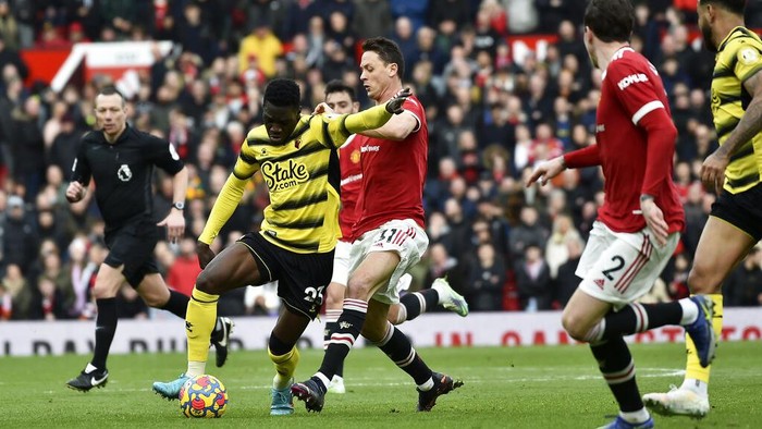 MU Ditahan Imbang Watford Tanpa Gol Watford's Emmanuel Dennis vies for the ball with Manchester United's Aaron Wan-Bissaka, center, during the English Premier League soccer match between Manchester United and Watford at Old Trafford in Manchester, England, Saturday, Feb. 26, 2022. (AP Photo/Rui Vieira)